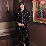 Modal wearing Black Long-Sleeved Women's Pajama Set in Halloween Friends print standing in a living room ::: Model is 5'9" wearing size S /// ---1605 3