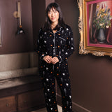Modal wearing Black Long-Sleeved Women's Pajama Set in Halloween Friends print standing in a living room ::: Model is 5'9" wearing size S /// ---1605 3