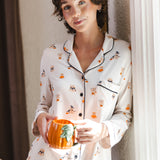 Modal standing against a wall holding a cup wearing a Beige Long-Sleeved Women's Pajama Set in Halloween Teddy print ---PJ 4