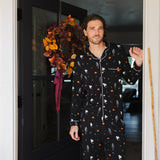 Model wearing Men's Long Sleeve Pajama Set in Halloween Friends print standing in doorway 
