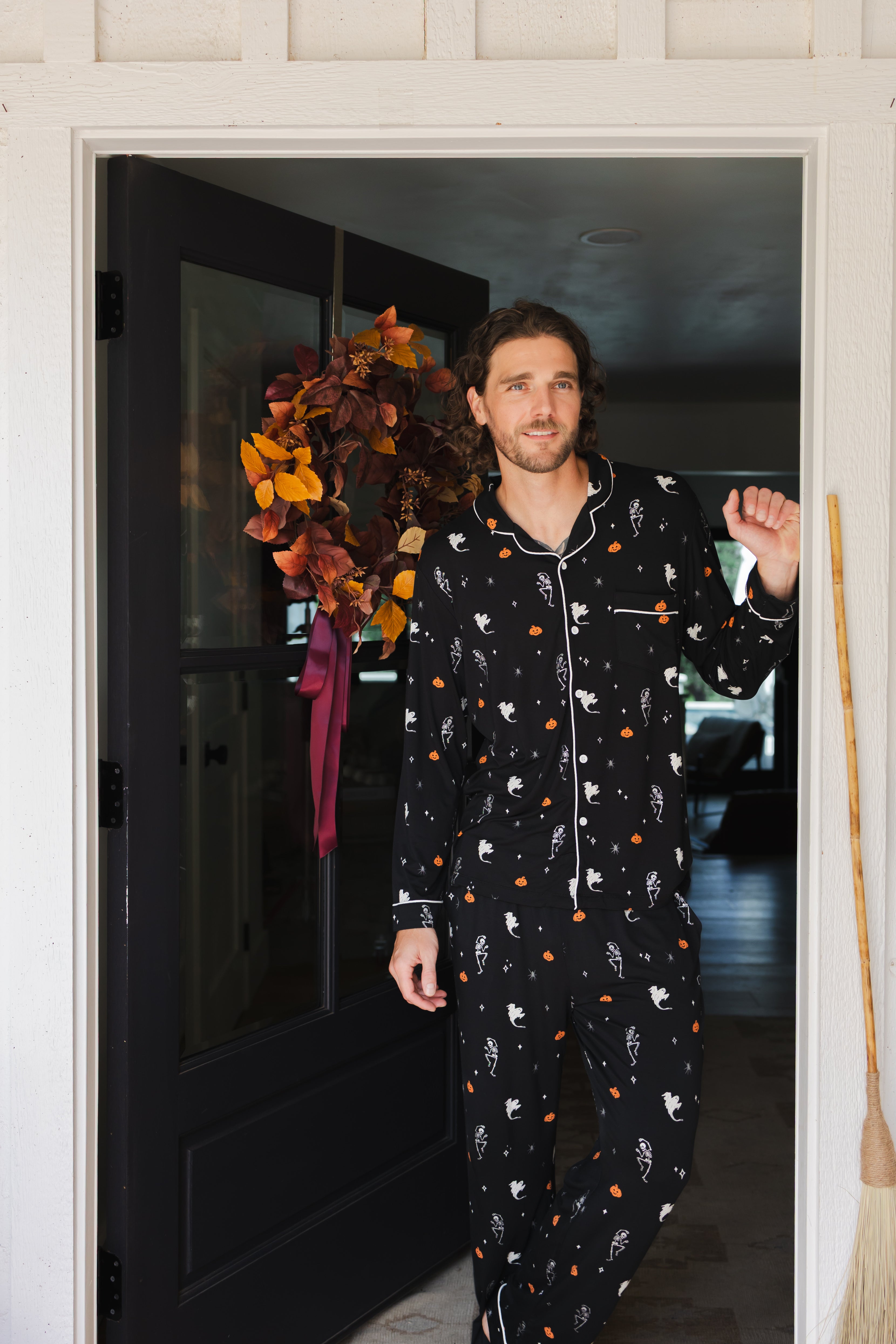 Model wearing Men's Long Sleeve Pajama Set in Halloween Friends print standing in doorway 