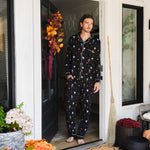 Model wearing Men's Long Sleeve Pajama Set in Halloween Friends print standing in doorway 