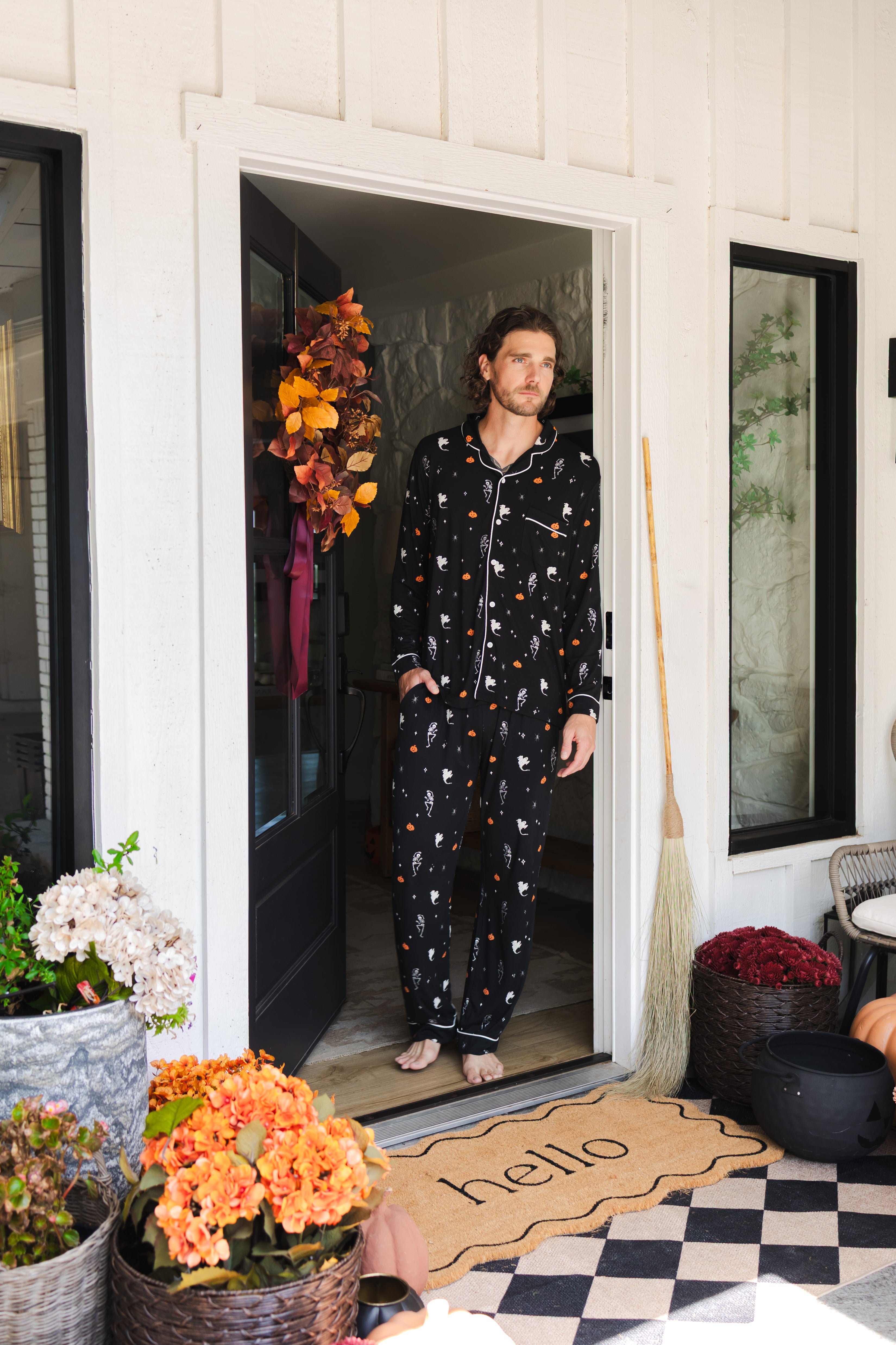 Model wearing Men's Long Sleeve Pajama Set in Halloween Friends print standing in doorway 