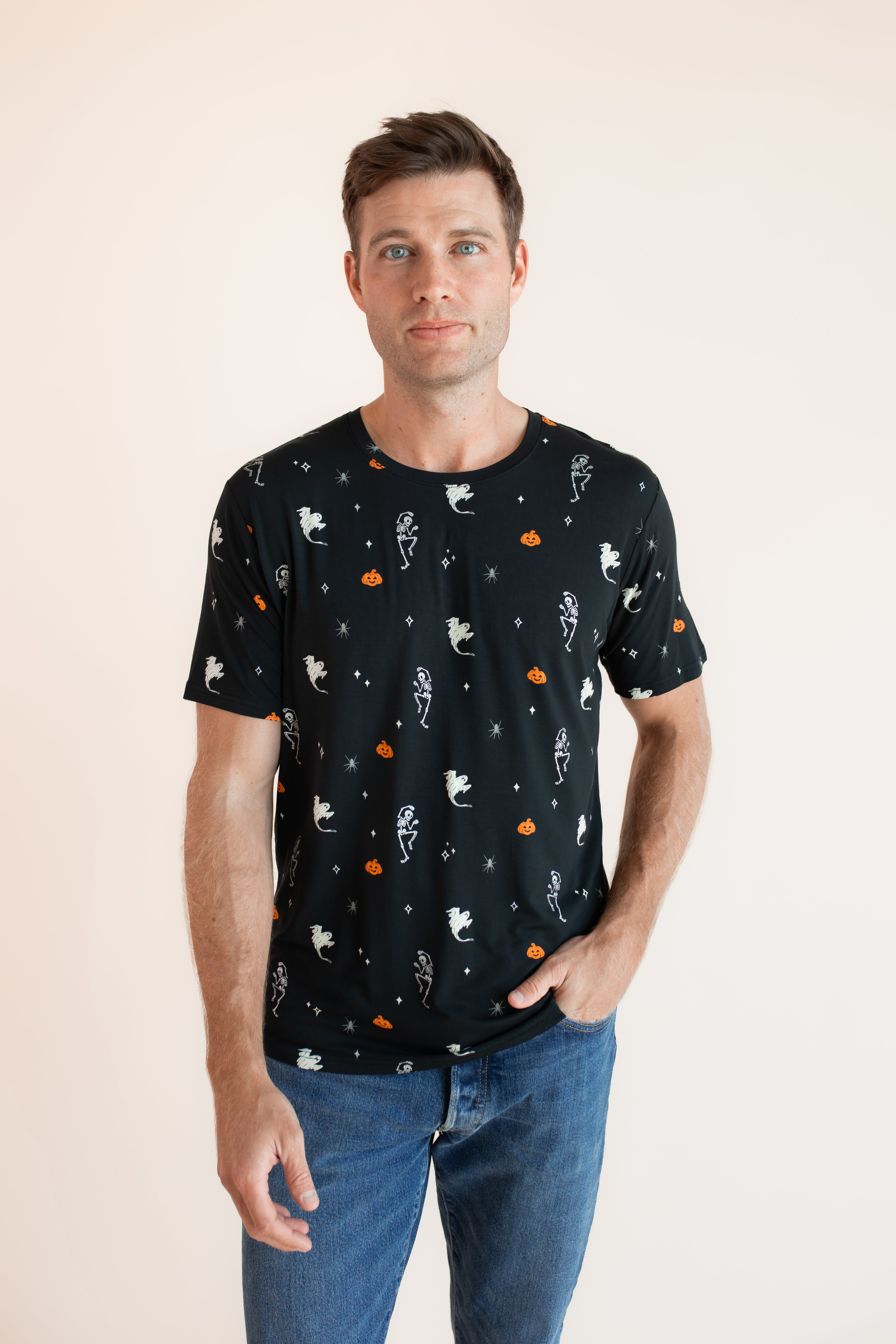 Modal posing wearing Men's Crew Neck Tee in Halloween Friends print over blue jeans on a beige background 