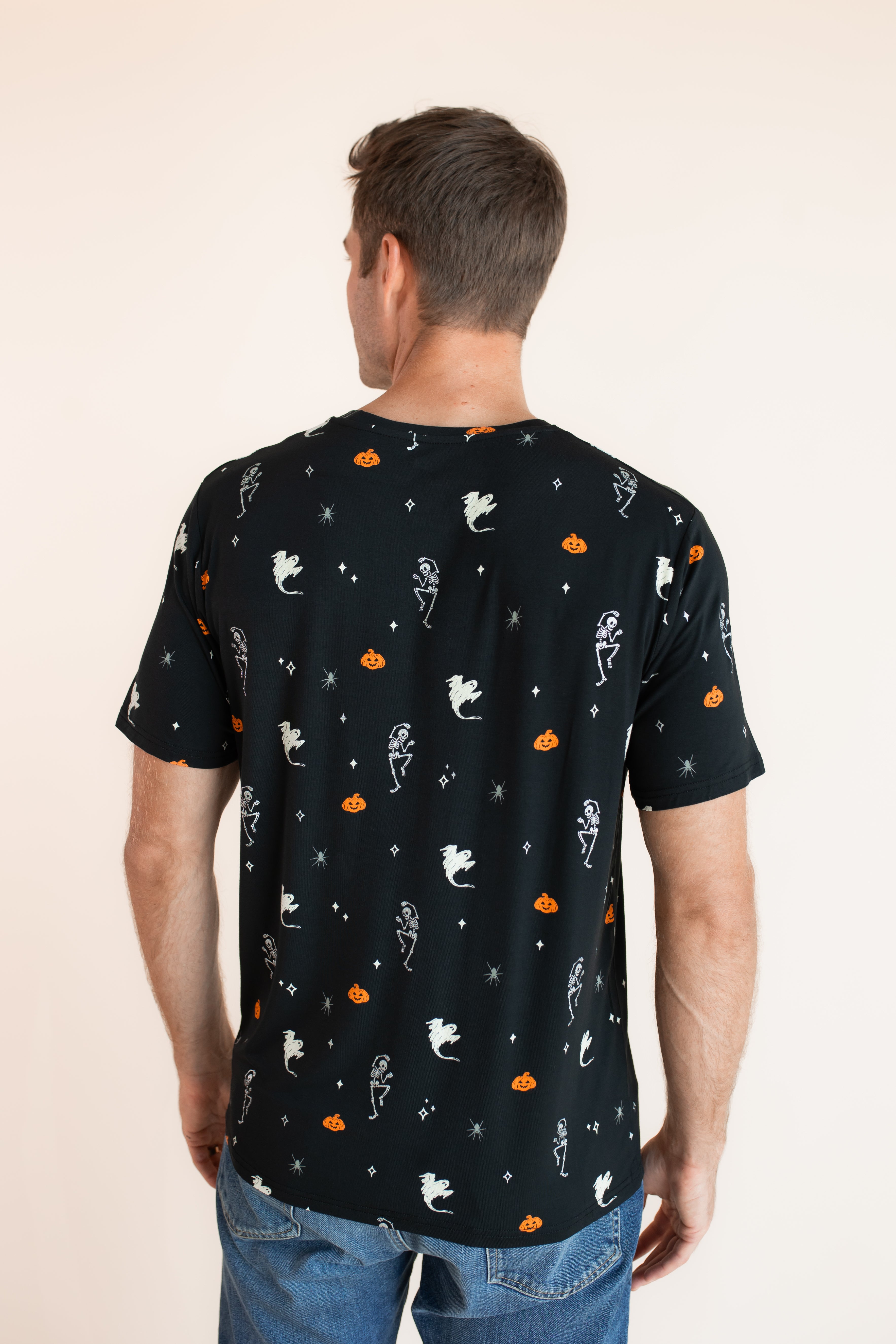 Back side of Modal wearing Men's Crew Neck Tee in Halloween Friends print over blue jeans on a beige background