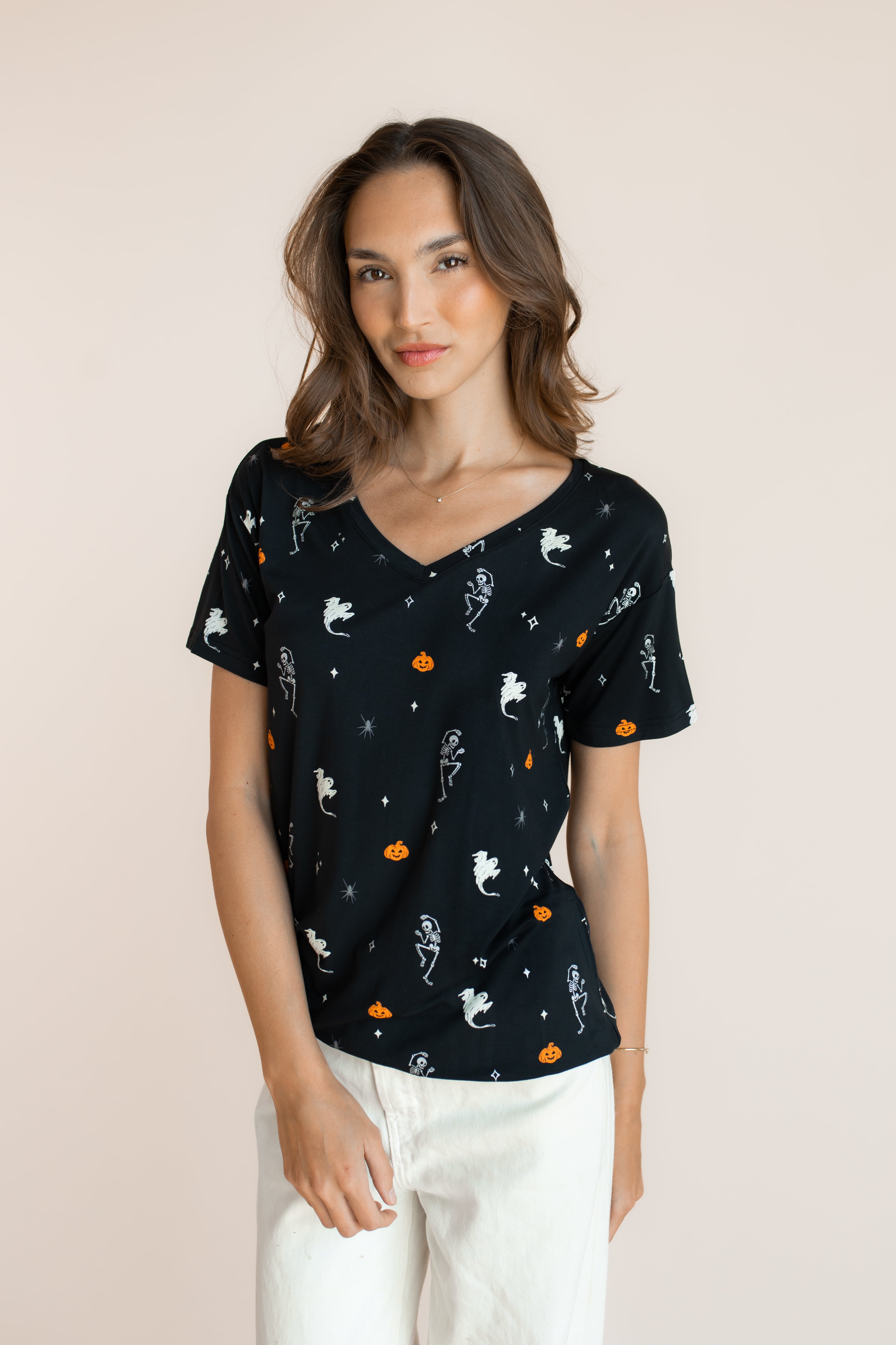 Modal wearing Women's Oversized V-Neck Tee in Halloween Friends print over white pants on a beige background 