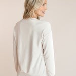 Back side of Modal wearing off white Women's Sweatshirt with Halloween Teddy print over white pants on a beige background