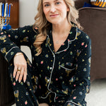 Woman wearing black long sleeve pajama set printed with Hanukkah elements 