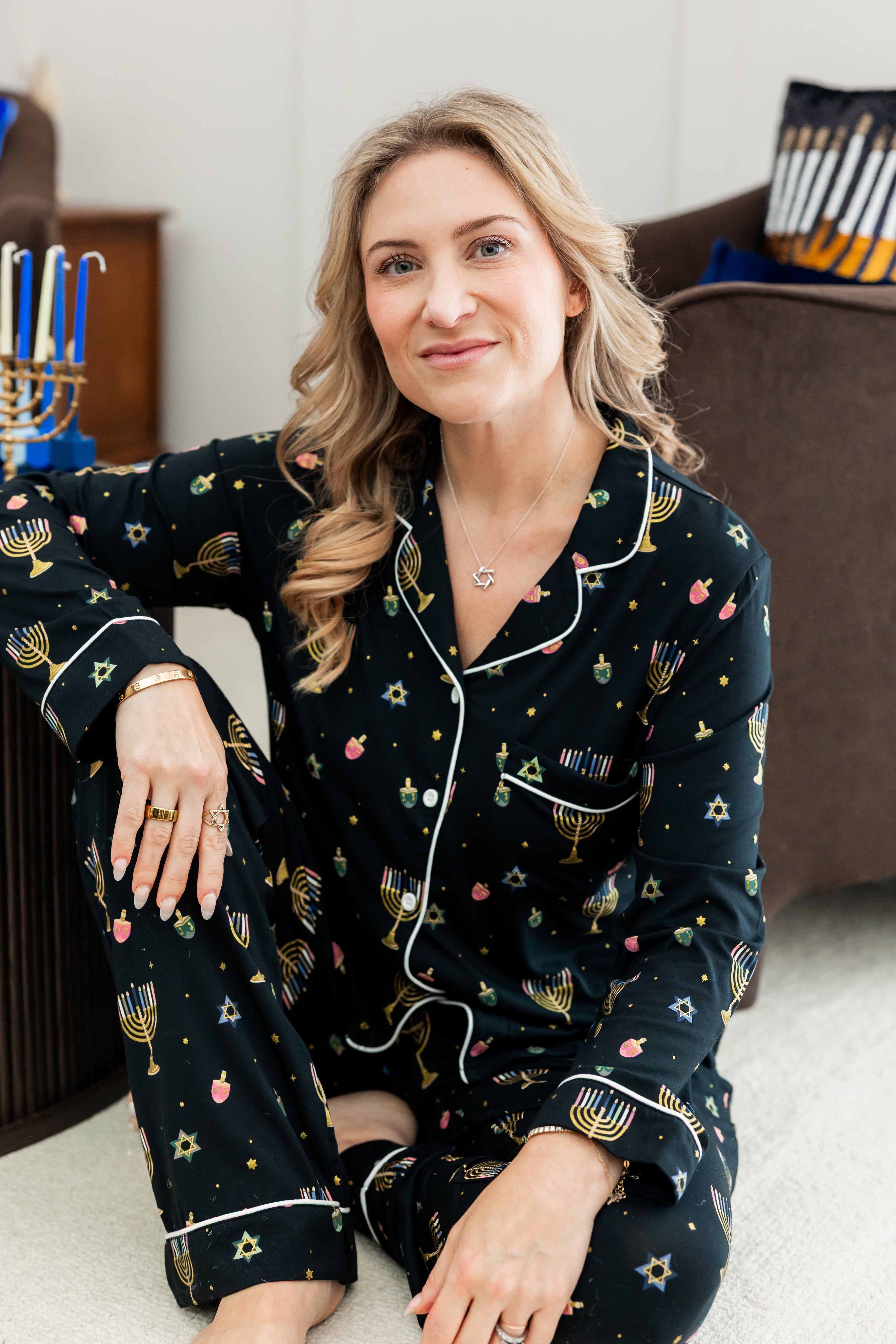 Woman wearing black long sleeve pajama set printed with Hanukkah elements 