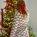 Woman putting a bow on a Christmas tree while modeling the back of the Bamboo Long-Sleeved Women's Pajama Set in Holiday Bow
