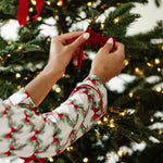 Close up of the arms of the top of the Bamboo Long-Sleeved Women's Pajama Set in Holiday Bow putting a bow in a tree