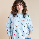 Woman wearing Women's Sweatshirt in Holiday Pups print over blue jeans on a beige background