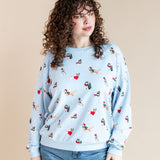 Woman posing in Women's Sweatshirt in Holiday Pups print over blue jeans on a beige background