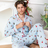Man sitting in a living room while buttoning the Men's Long Sleeve Pajama Set in Holiday Pups print