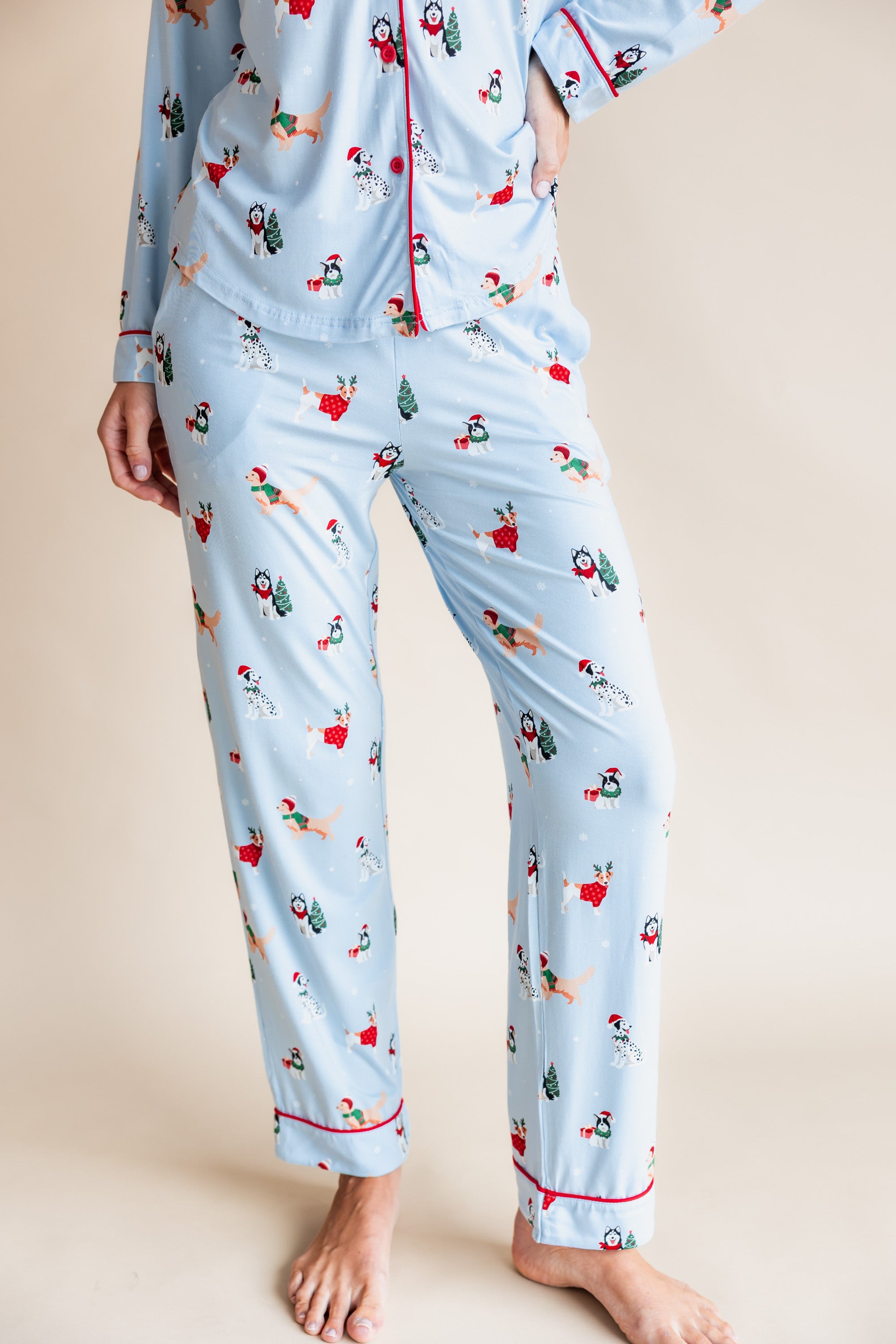Woman showcasing the front side of Long-Sleeved Women's Pajama Set in Holiday Pups print on a beige background
---1605 3