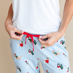 Woman showcasing the red drawstring on Women's Lounge Pants in Holiday Pups print under white T-shirt on a beige background
