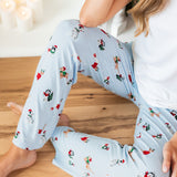 Woman wearing Women's Lounge Pants in Holiday Pups print under white T-shirt while sitting on the wooden floor