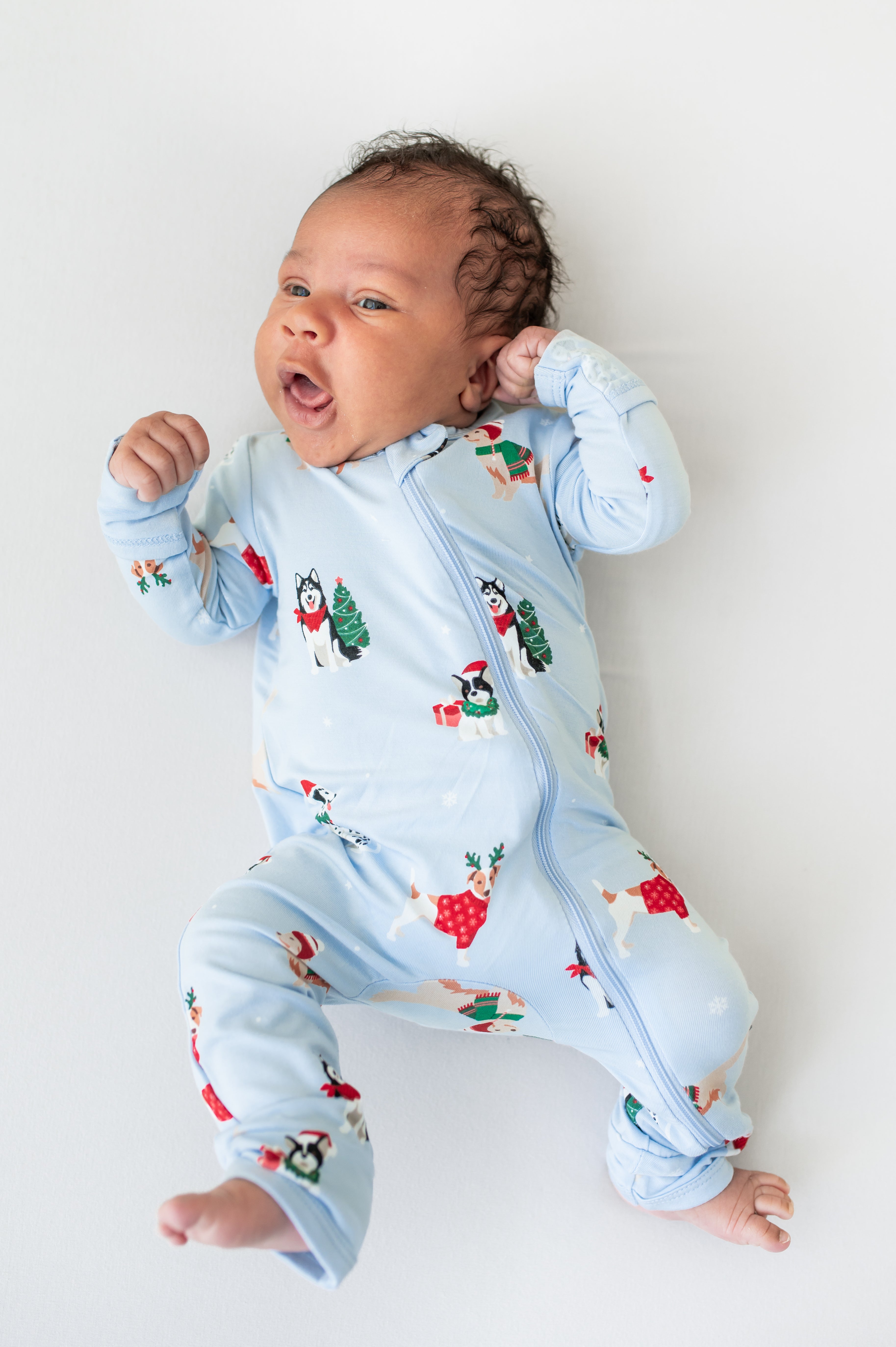 Baby wearing Zippered Romper in Holiday Pups print on a white background