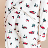 The back of a woman with her leg propped in long sleeve pajama set in holiday tree farm
