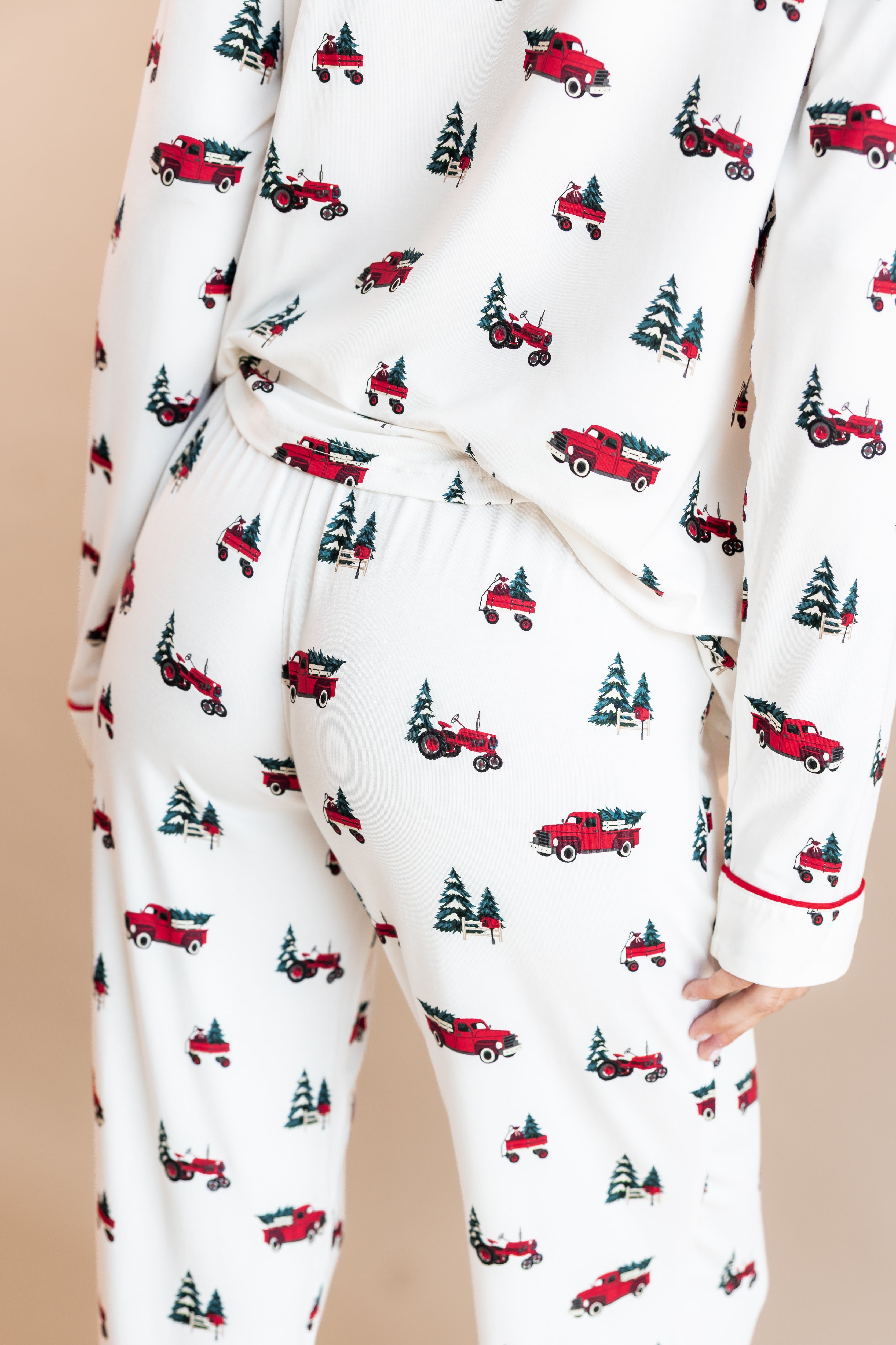 The back of a woman with her leg propped in long sleeve pajama set in holiday tree farm