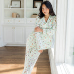 Woman leaning against large window while modeling the Long-Sleeved Women's Pajama Set in Honeydukes

::: Model is 5'2" wearing size S ///