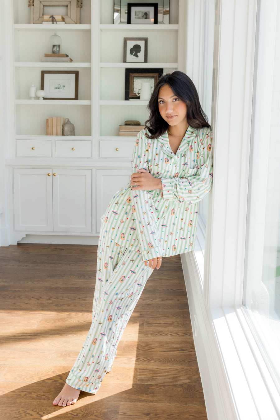 Woman leaning against large window while modeling the Long-Sleeved Women's Pajama Set in Honeydukes