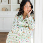 Woman wearing green striped pajamas with honeydukes harry potter pattern in a bright living room
::: Model is 5'2" wearing size S ///