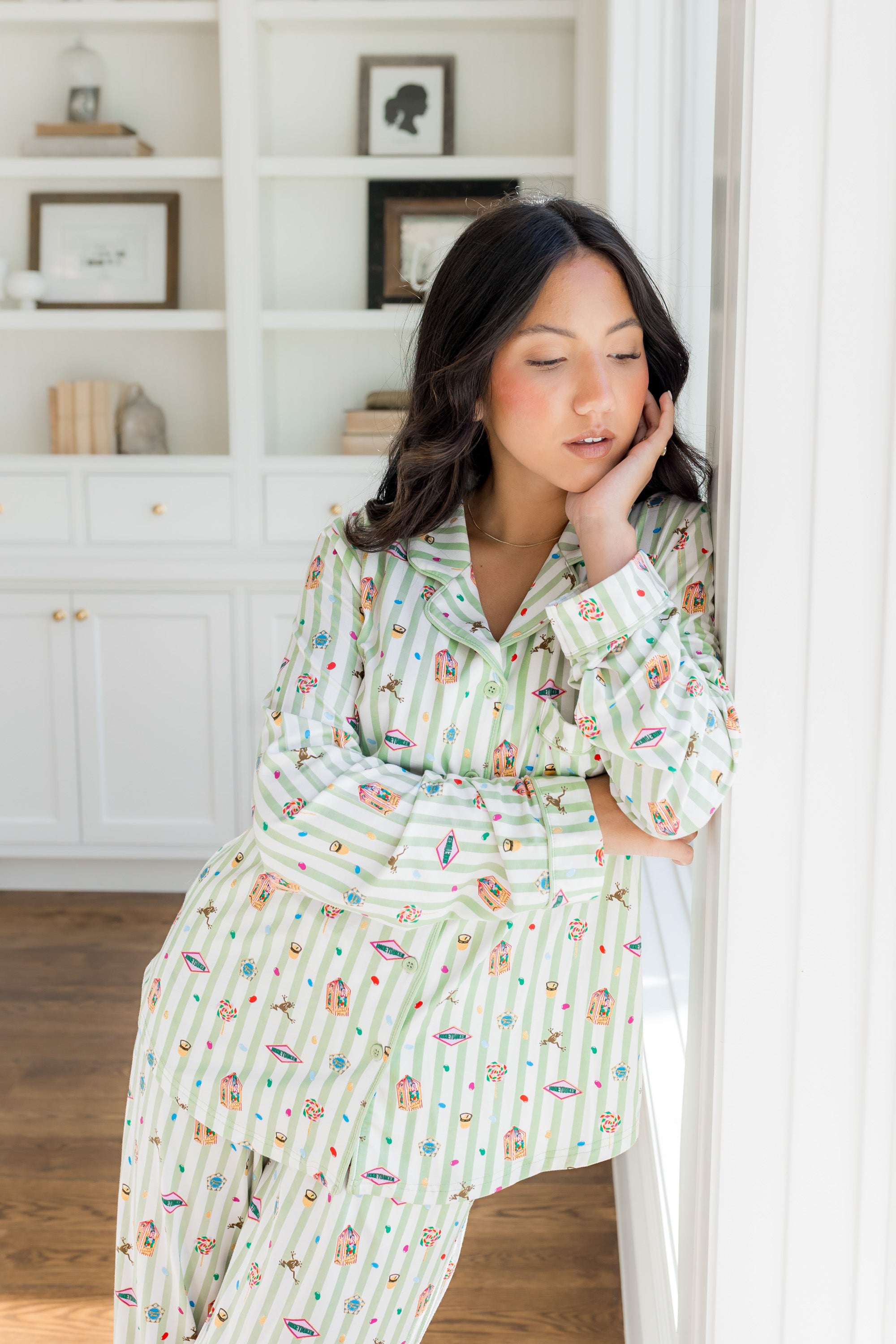 Woman wearing green striped pajamas with honeydukes harry potter pattern in a bright living room
