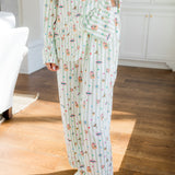Person wearing Long-Sleeved Women's Pajama Set with colorful Harry Potter patterns on a green and white striped fabric.