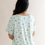 Back side of Women's Relaxed Fit V-Neck having colorful Harry Potter patterns on a green and white striped fabric on a beige background