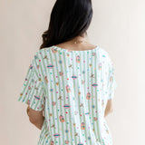 Back side of Women's Relaxed Fit V-Neck having colorful Harry Potter patterns on a green and white striped fabric on a beige background