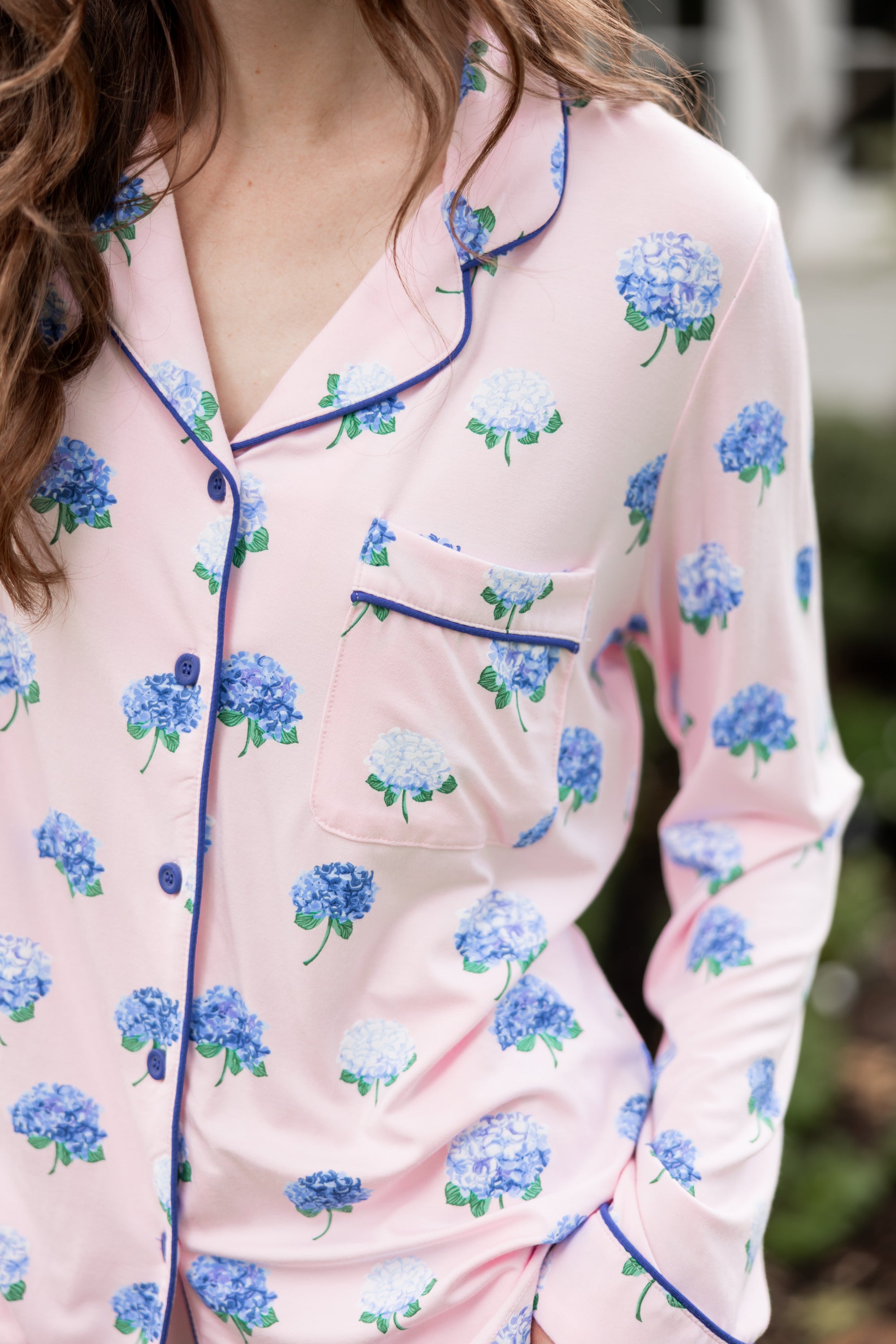 Woman outside with her hand in her pocket wearing a long sleeve pajama top in Hydrangea Sakura print. ---PJ 2