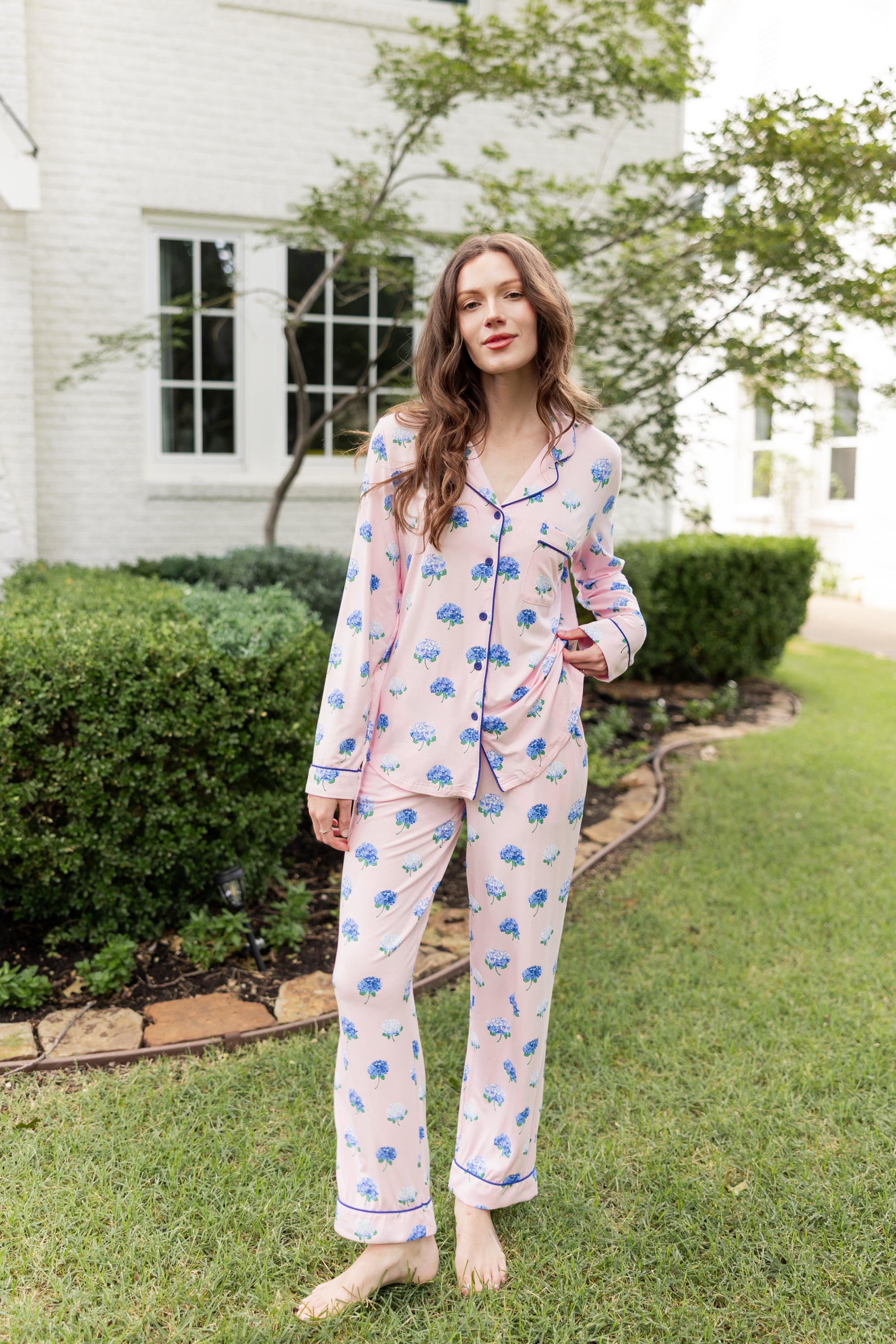 Woman outside with her leg propped and hand on her top in long sleeve pajamas in Hydrangea Sakura print.
---1605 3