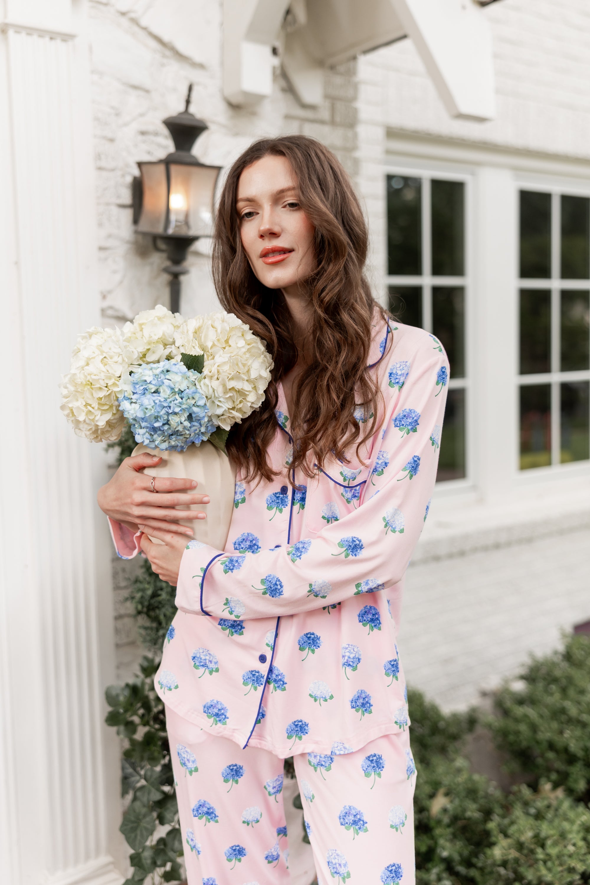 Woman outside holding a vase of hydrangeas in long sleeve pajamas in Hydrangea Sakura print.
 ---PJ 4