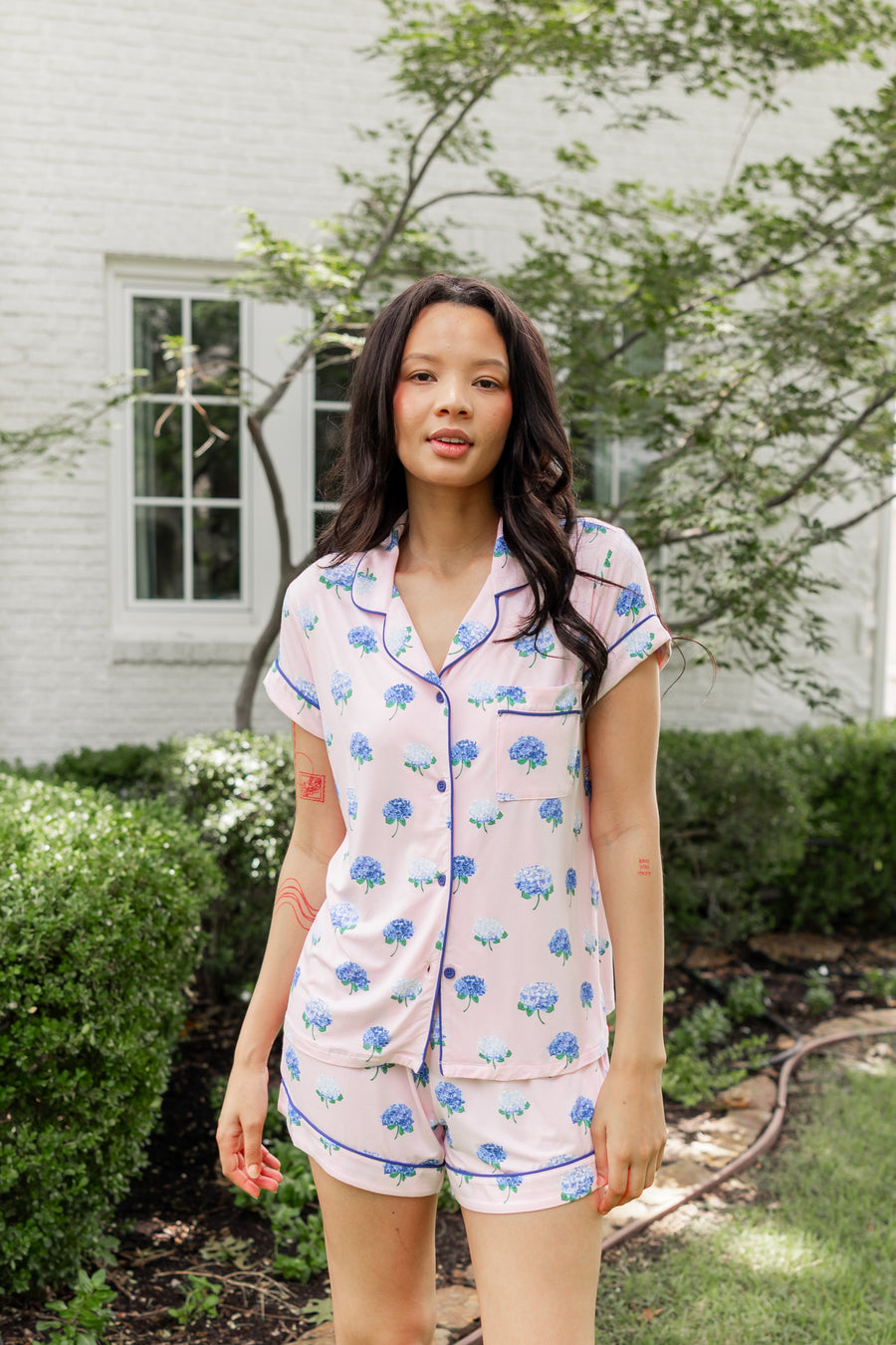 Woman outside soft smiling in short sleeve and short pajamas in Hydrangea Sakura print.