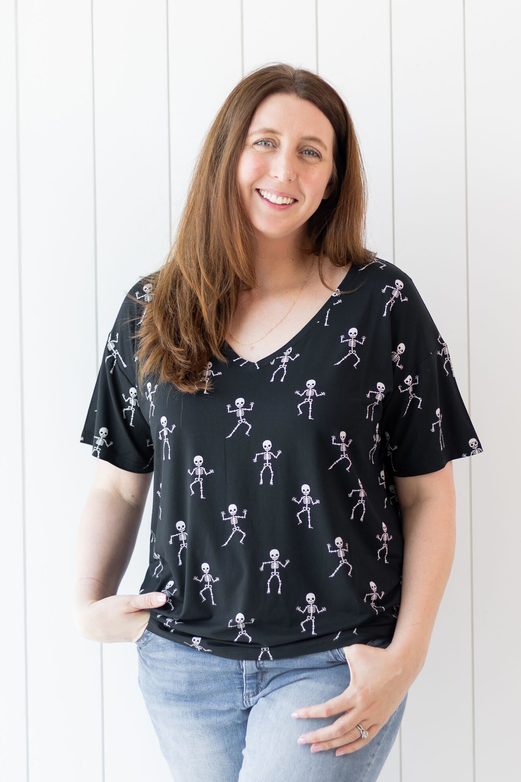 Model smiling while wearing the Women's V-Neck in Skeleton paired with light jeans