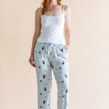 Model in blue Women's Lounge Pants in Sushi print under white camisole on a beige background