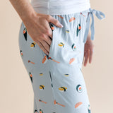 Model showing pockets of blue Women's Lounge Pants in Sushi print under white camisole on a beige background