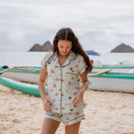 Model standing on the beach looking down while wearing the Kyte Short Sleeve Pajama Set in Dew Surf