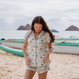 Model standing on the beach looking down while wearing the Kyte Short Sleeve Pajama Set in Dew Surf