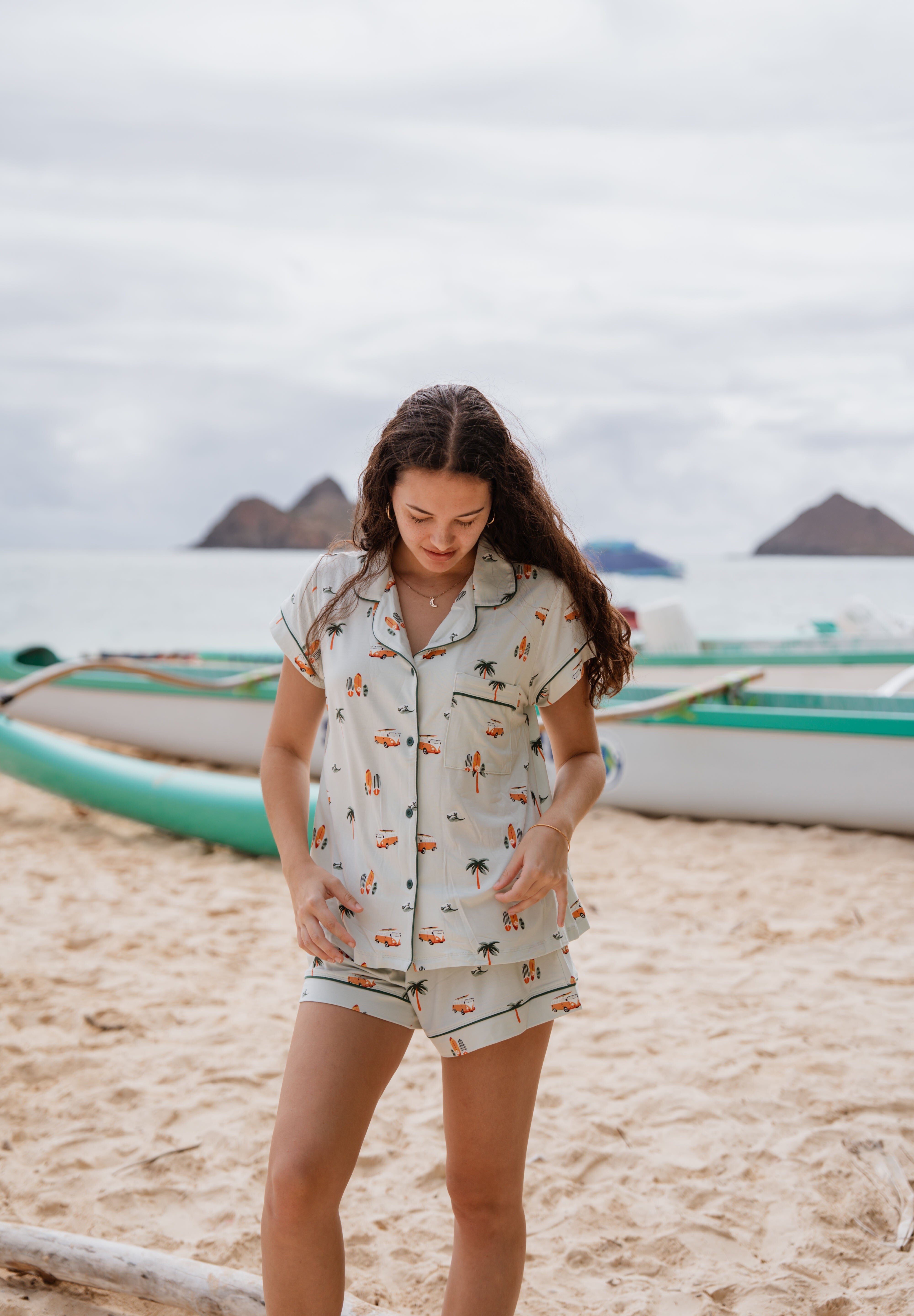 Model standing on the beach looking down while wearing the Kyte Short Sleeve Pajama Set in Dew Surf