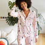 Woman wearing a pink pajama set with sushi print in a cozy living room.
---PJ 4
