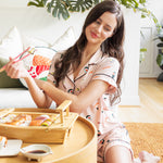 Woman in pajamas enjoying a meal of sushi in a cozy living room.