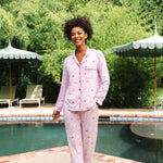 Smiling model standing in front of a pool while modeling the Long-Sleeved Women's Pajama Set in Cocktail