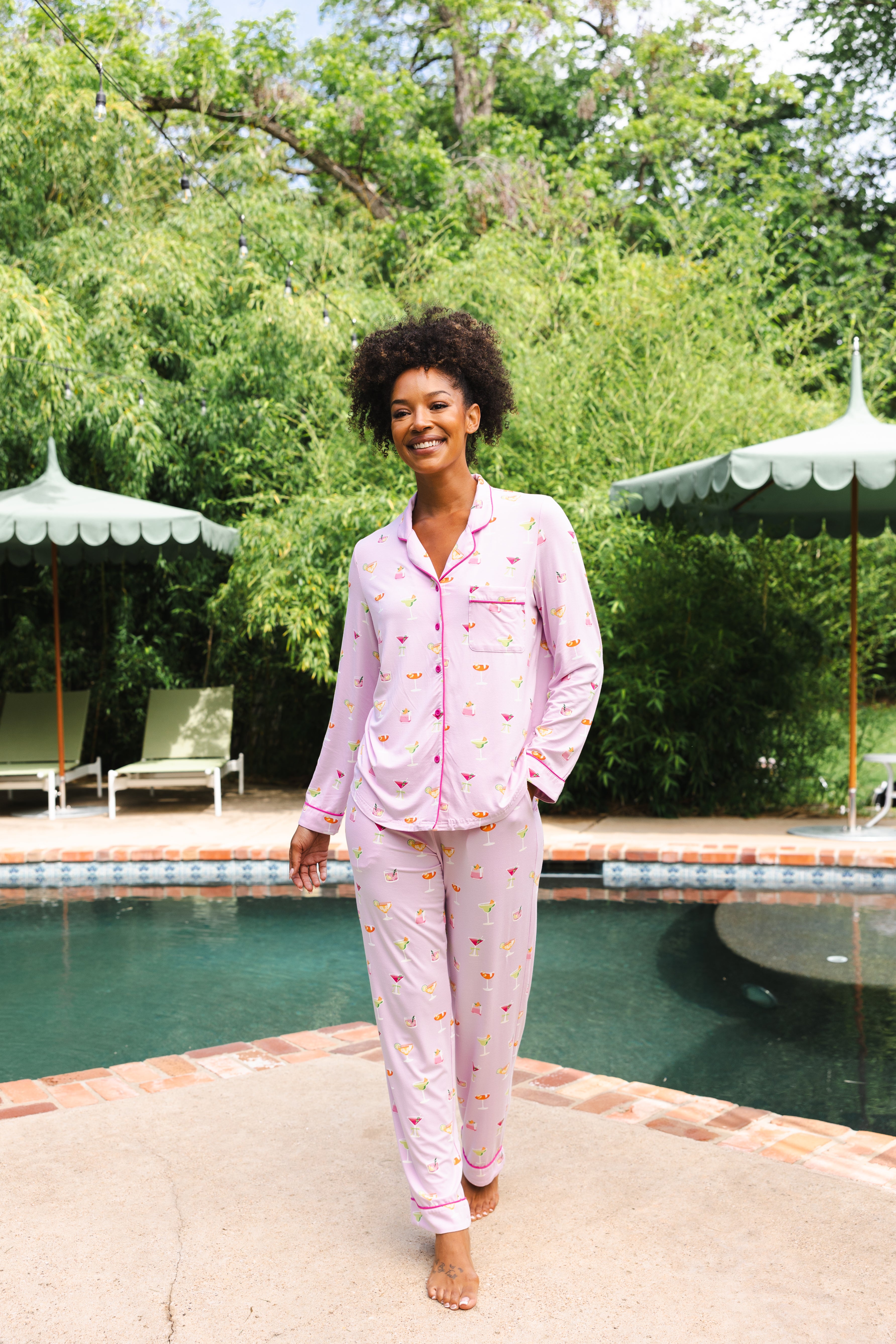 Smiling model standing in front of a pool while modeling the Long-Sleeved Women's Pajama Set in Cocktail