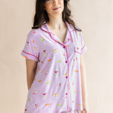 Woman standing in front of a beige back ground while modeling the Kyte Women's Short Sleeve Pajama Set in Cocktail

::: Model is 5'6" wearing size S ///