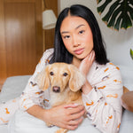 Woman in Long-Sleeved Women's Pajama Set in Dachshund holding a blonde dachshund on a couch with a plant in the background
---PJ 4