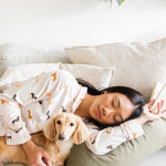 Sleeping model wearing the Long-Sleeved Women's Pajama Set in Dachshund while snuggled with a blonde dachshund 