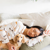 Sleeping model wearing the Long-Sleeved Women's Pajama Set in Dachshund while snuggled with a blonde dachshund 