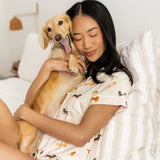 Woman holding blonde yawning dachshund while sitting on a white bed and modeling the Short Sleeve Pajama Set in Dachshund print 
::: Model is 5'6" wearing size XS ///

---PJ 4